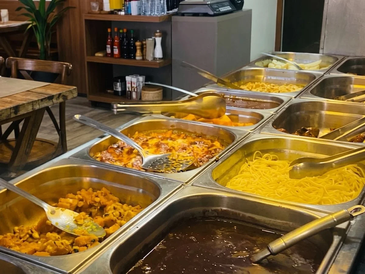 Cubas do buffet caseiro do Brazedo com massas, carnes e acompanhamentos