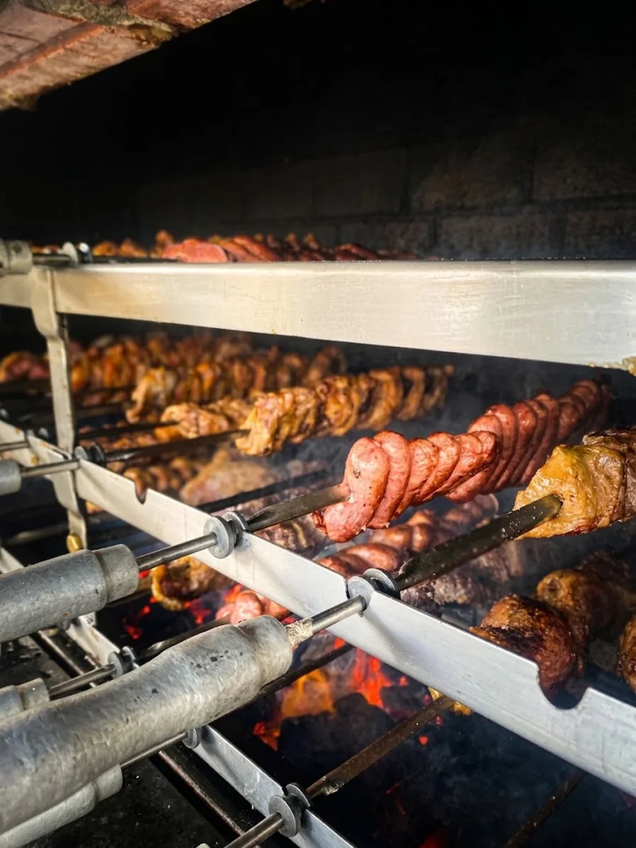 Espetos de carne e linguiça assando na brasa